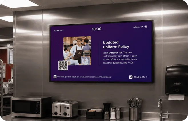 Interact digital signage in a staff break room announcing an updated uniform policy from October 1st with a QR code, showing 10:30 AM in Atlanta, GA.