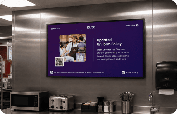 Interact digital signage in a staff break room announcing an updated uniform policy from October 1st with a QR code, showing 10:30 AM in Atlanta, GA.