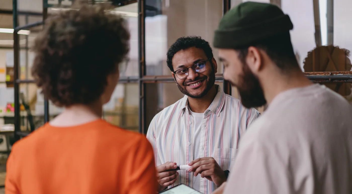 Colleagues chatting and smiling around a table in a modern office