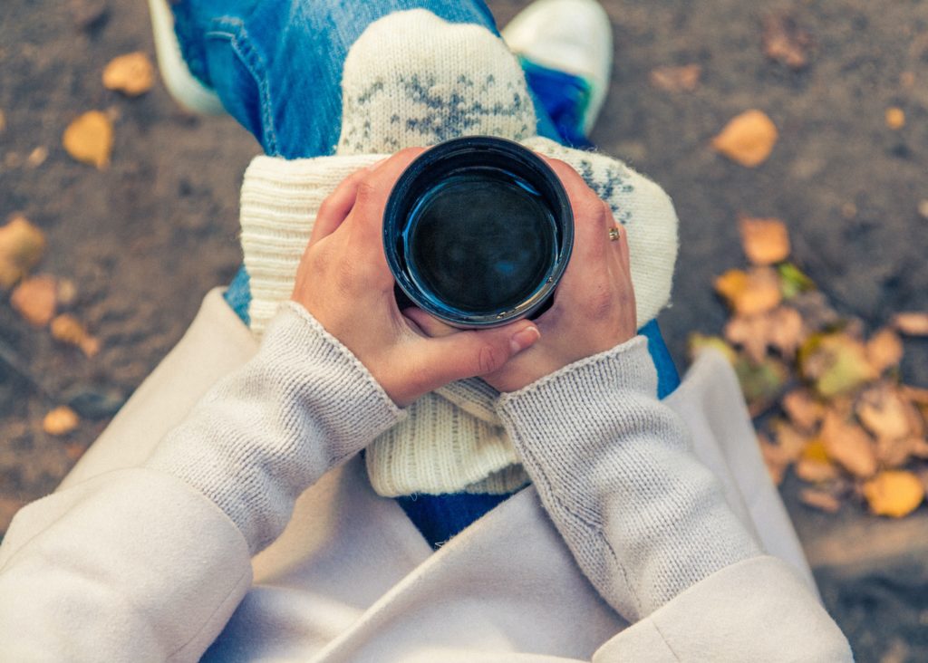 woman holding cup of tea whilst sat down