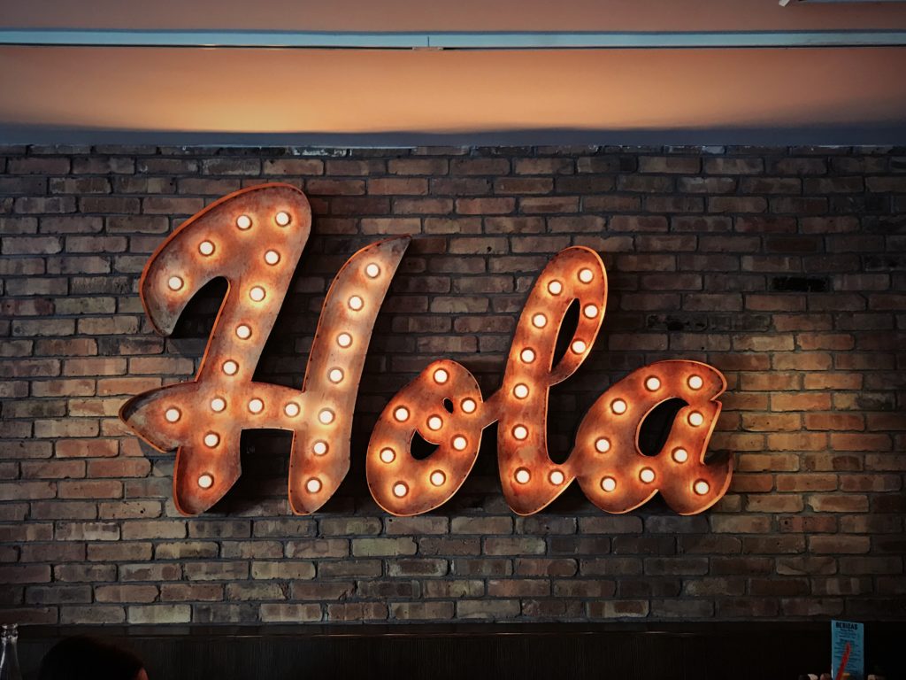 hola sign in lights on brick wall