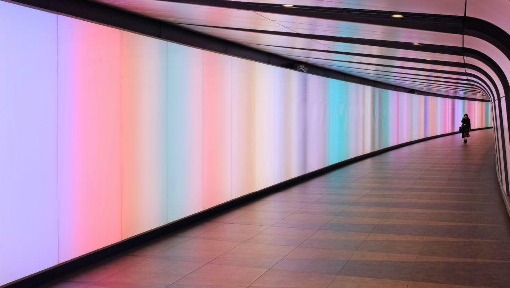 woman walking down neon lit tunnel