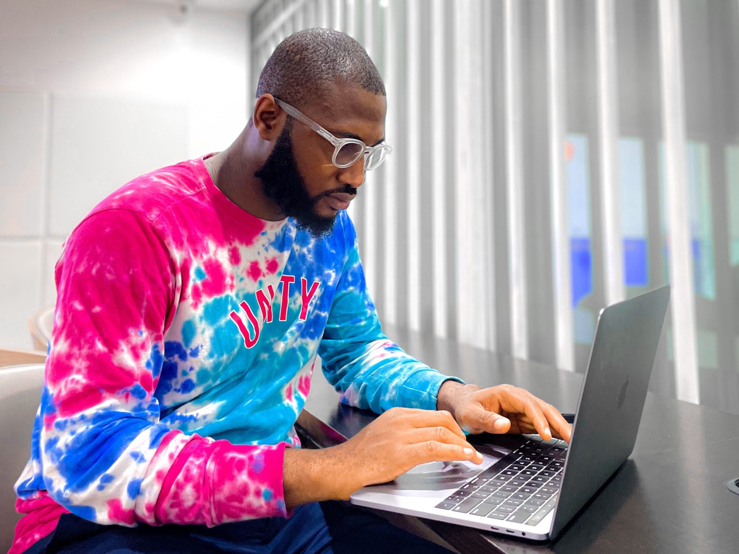 Man in colourful sweater works at laptop in stylish modern office
