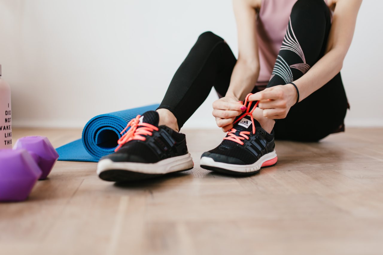 Woman in gym clothes ties laces in workout space