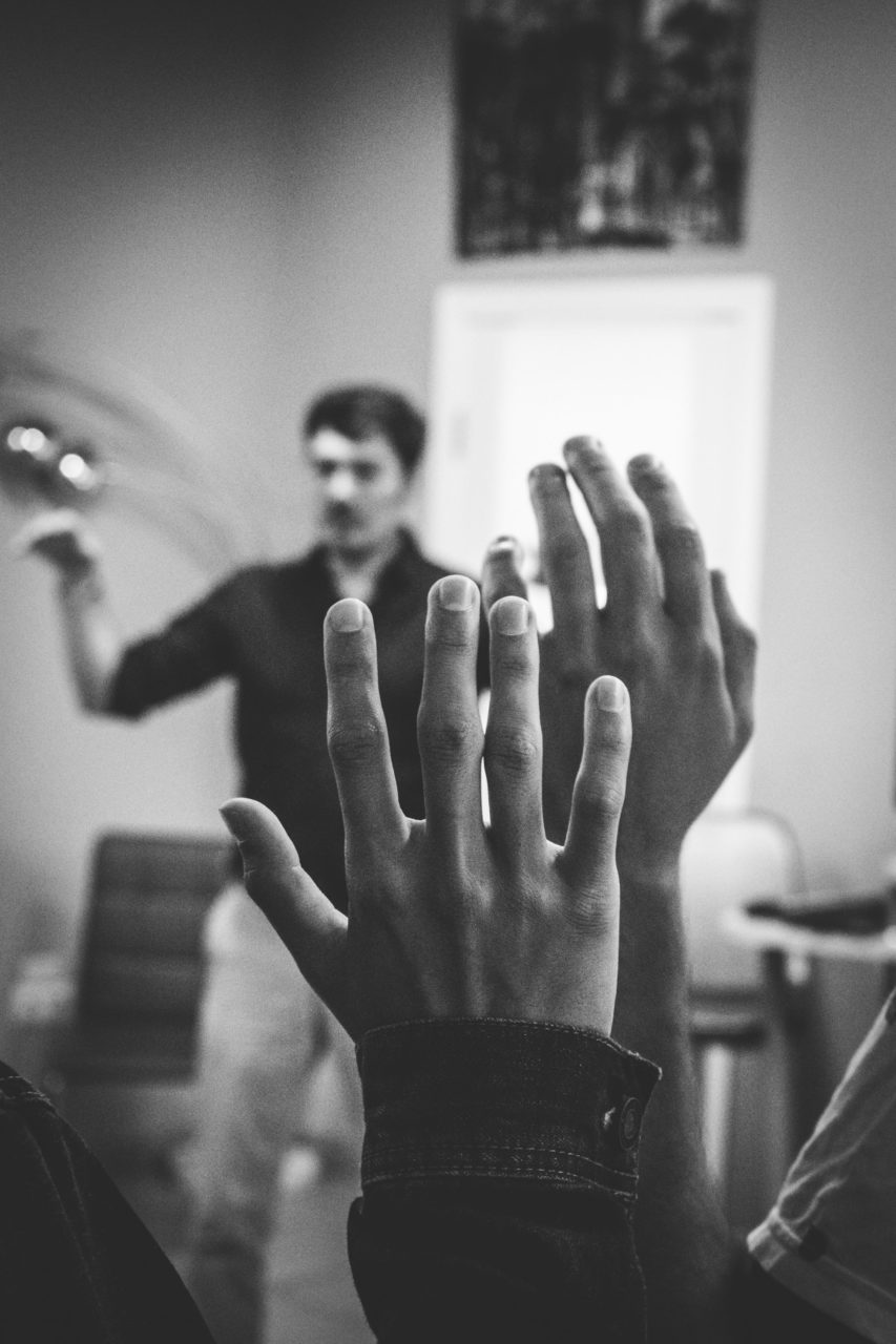 greyscale photo of people raising their hands