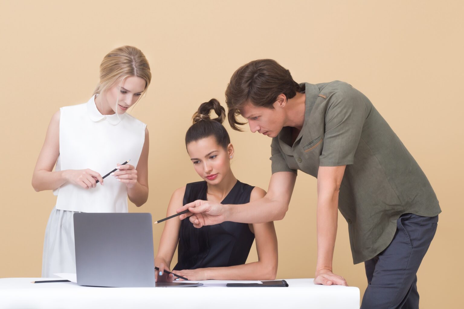 Three co-workers gathered at a laptop collaborating on an intranet request for proposal.