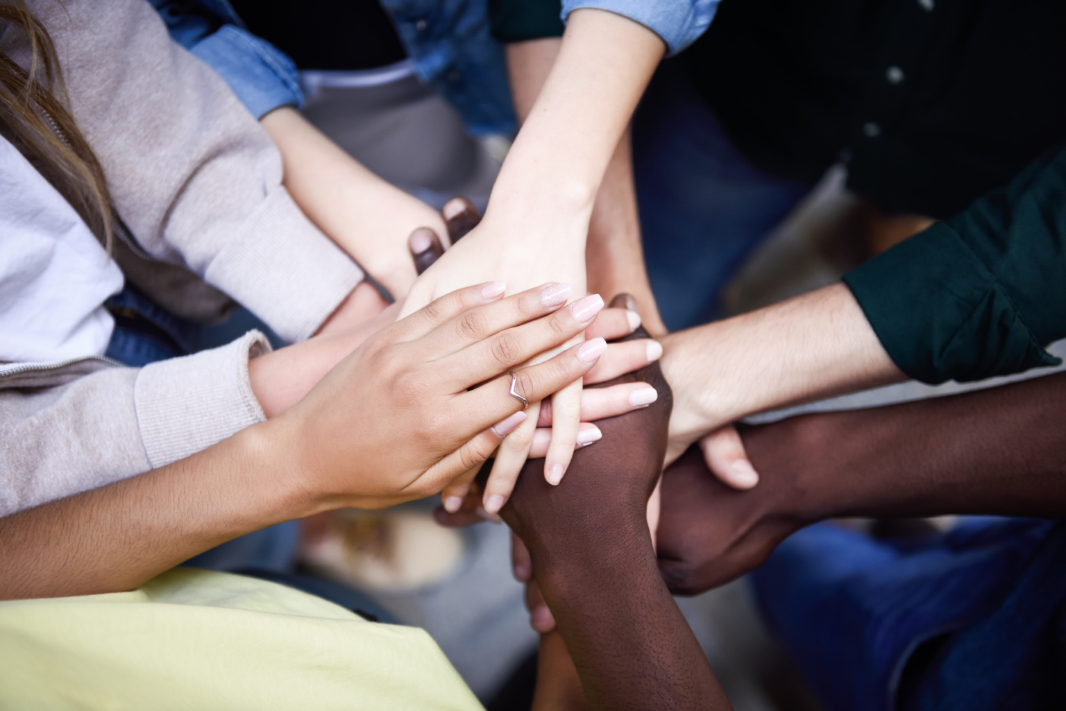 A group of diverse ethnicity placing their hands together representing what is DEI