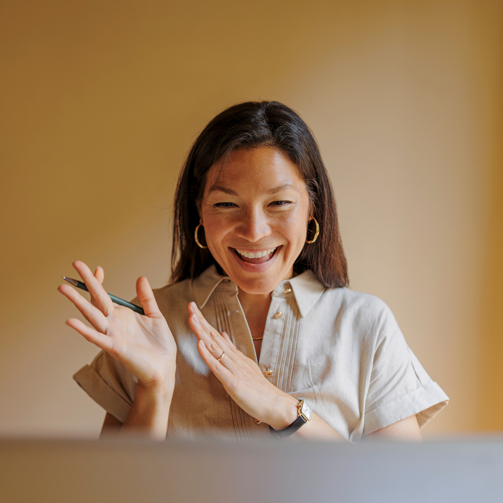 A woman smiling and gesturing animatedly during a video call, representing the friendly and responsive intranet support services Interact provides to customers.