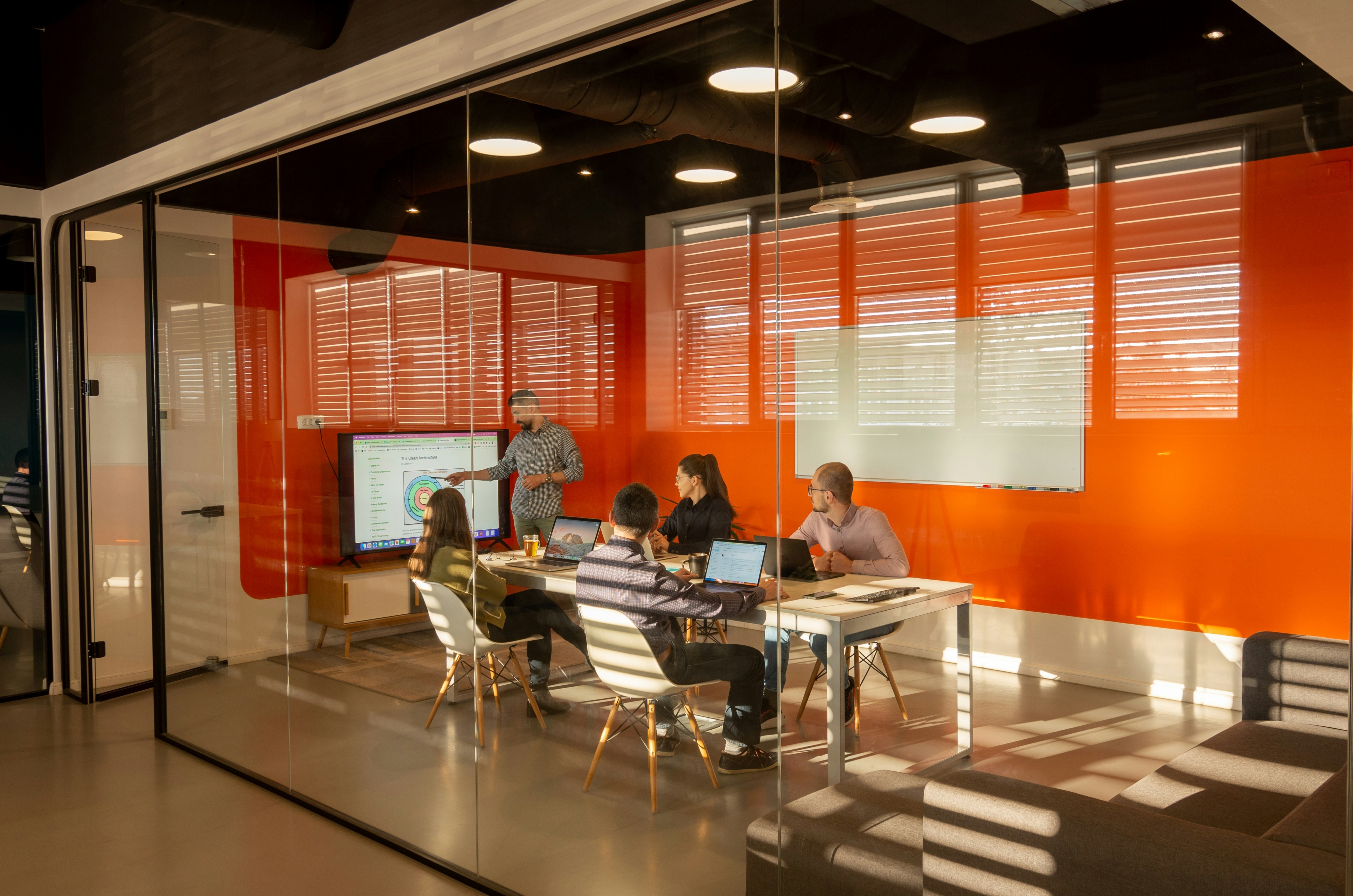 Young professional presenting strategic internal communications plan and results to colleagues in a glass meeting room